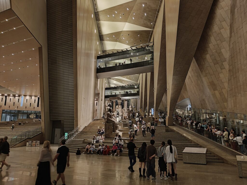 Visitors exploring the illuminated Grand Staircase inside the Grand Egyptian Museum