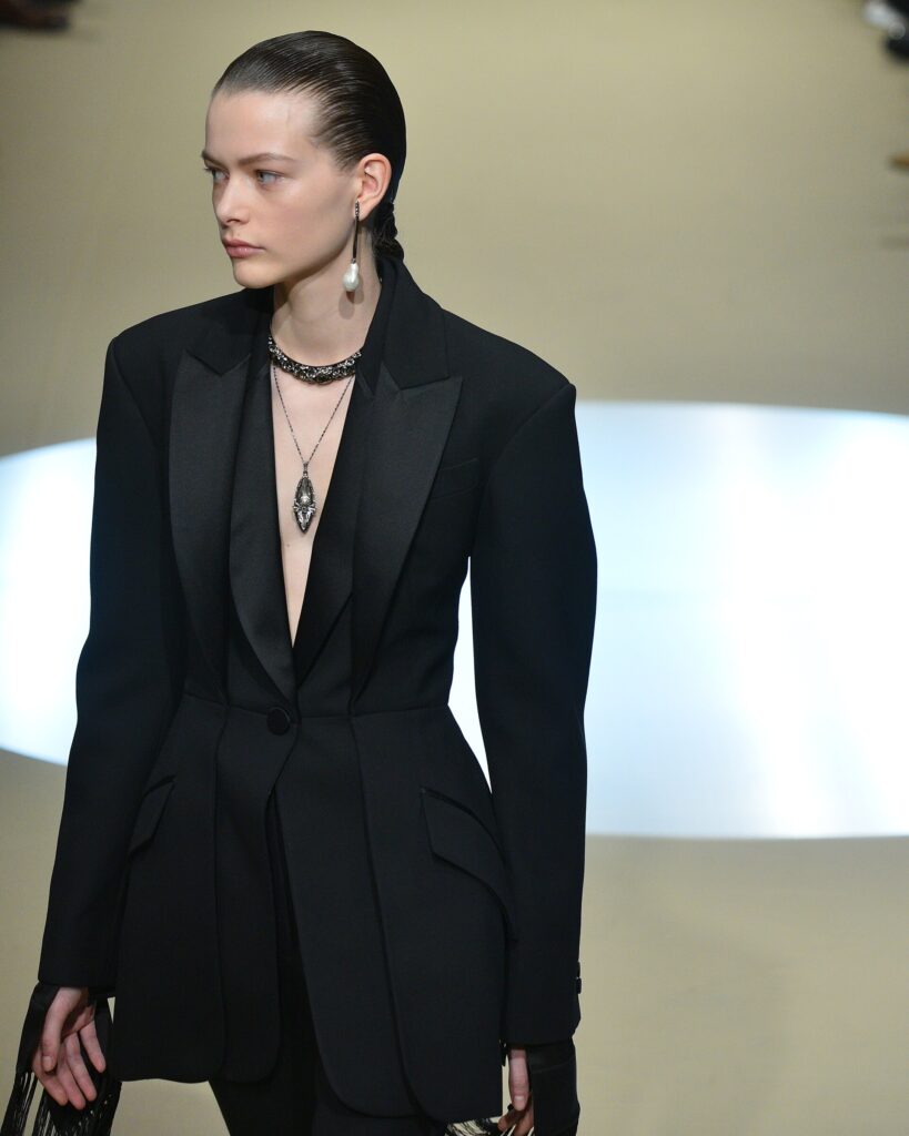 Model Louise Robert wearing sharp black tailoring on a Paris Fashion Week runway