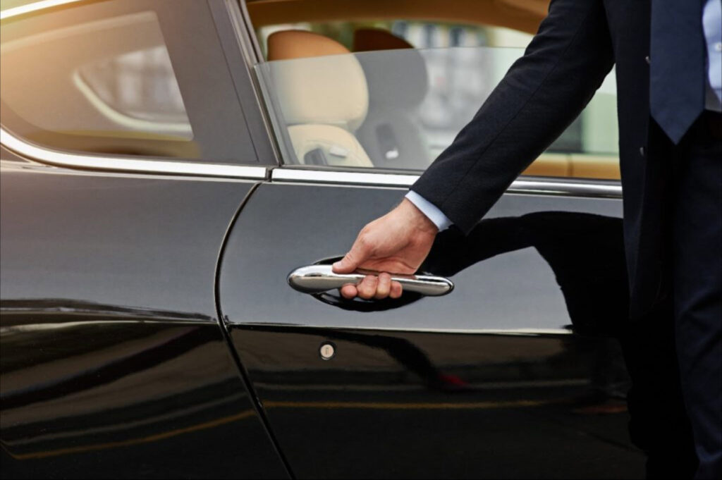 Professional chauffeur holding a personalised sign for an airport meet and greet