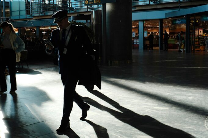 The Connected Traveller in a Modern Airport Business traveler using a smartphone in a modern airport during the rise of AI travel planning