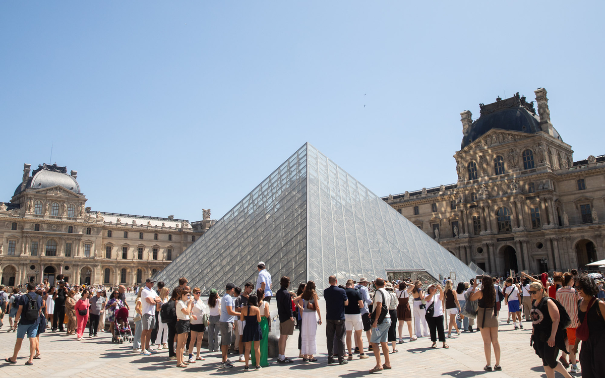 Visiteurs autour de la pyramide du Louvre pendant la saison touristique 2025 à Paris