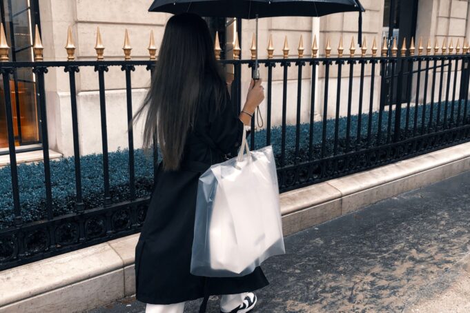 Luxury shopping in Paris — Avenue Montaigne Luxury shopper with an umbrella and shopping bags on Avenue Montaigne in Paris