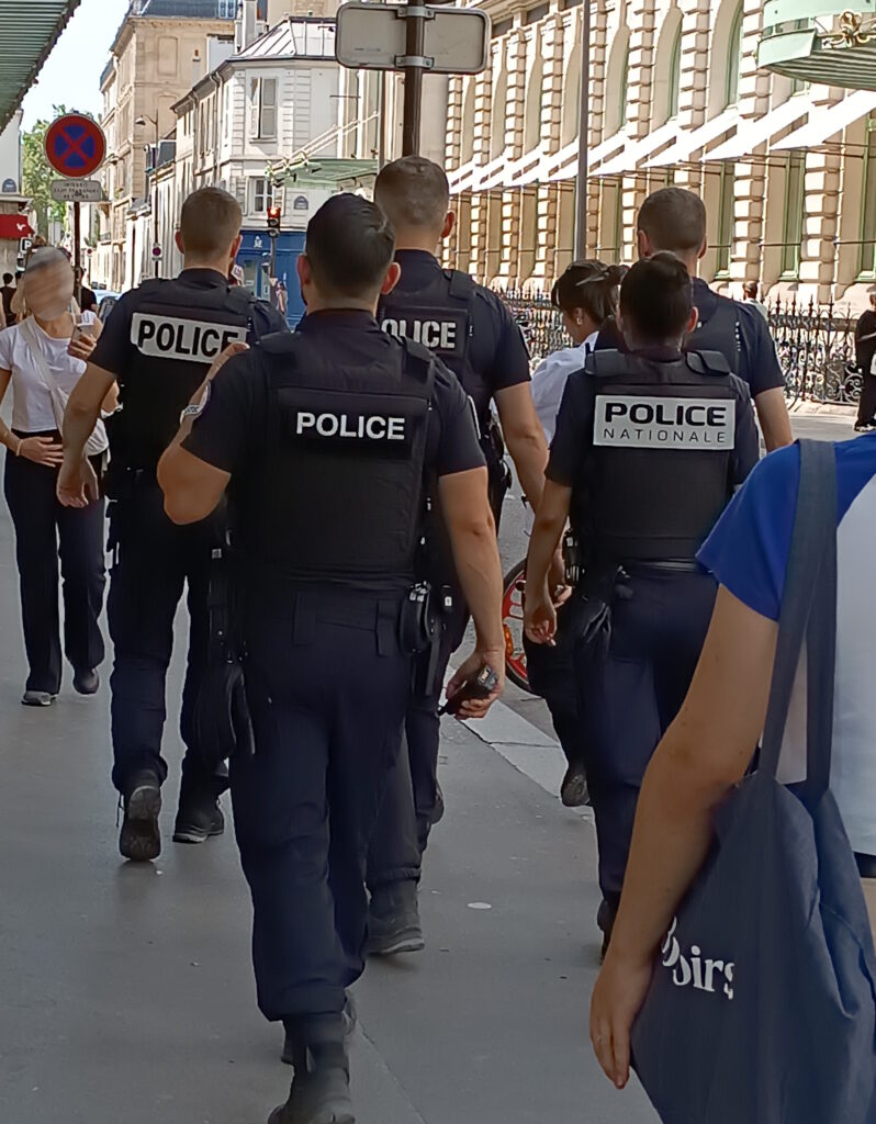 French National Police officers on foot patrol in a busy Paris street during the 2024 summer season