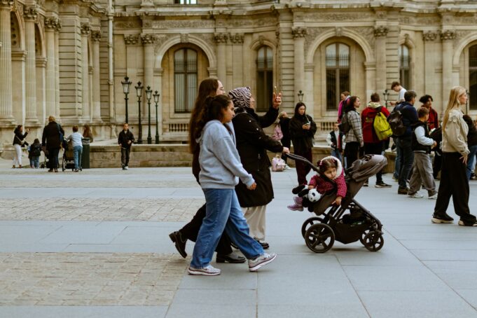 Des familles devant le Louvre : une journée parisienne se pense autrement lorsqu’elle rassemble générations, culture et temps partagé. Familles se promenant devant le musée du Louvre à Paris pendant l’été