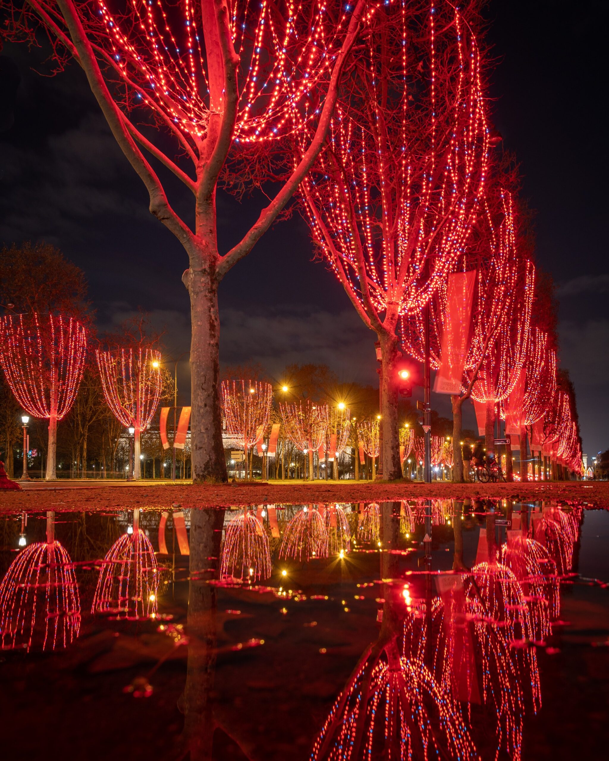 Illuminations rouges réelles des Champs-Élysées reflétées dans une flaque