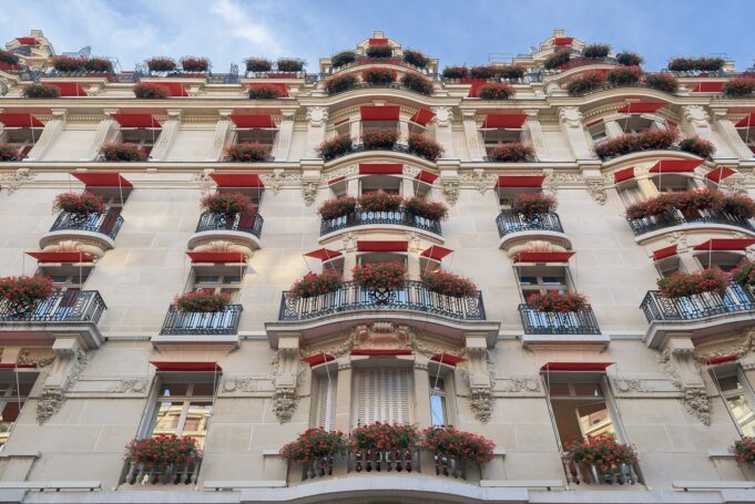 Hôtel Plaza Athénée red balconies in Paris Hôtel Plaza Athénée façade with red awnings and geraniums on avenue Montaigne in Paris