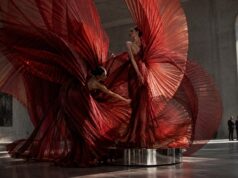 Fashion Week de Paris 2026 sans invitation : directs, événement public et rues à surveiller Two models surrounded by monumental red pleated couture in a Paris gallery