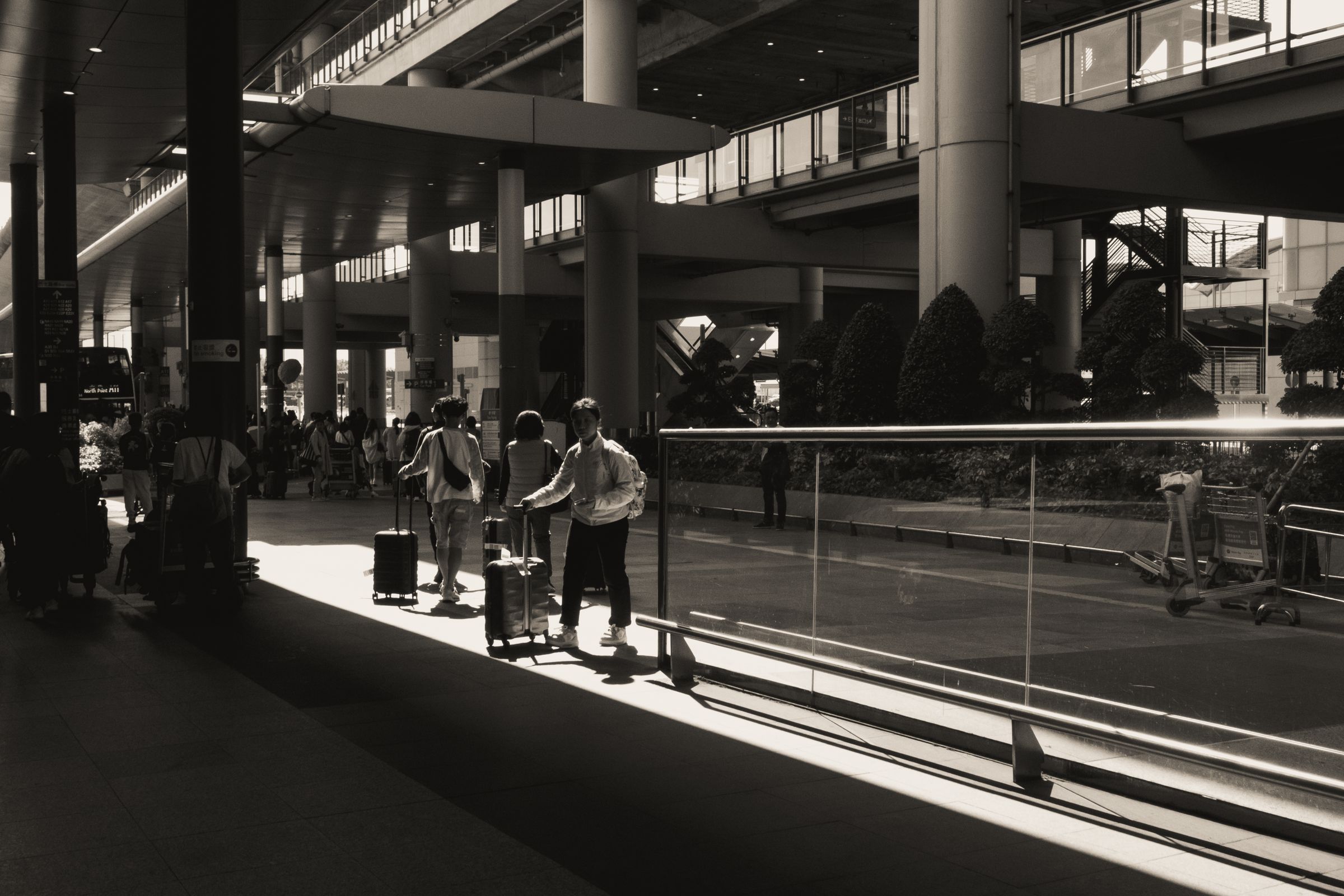 Travellers with luggage silhouetted in a sunlit modern airport terminal