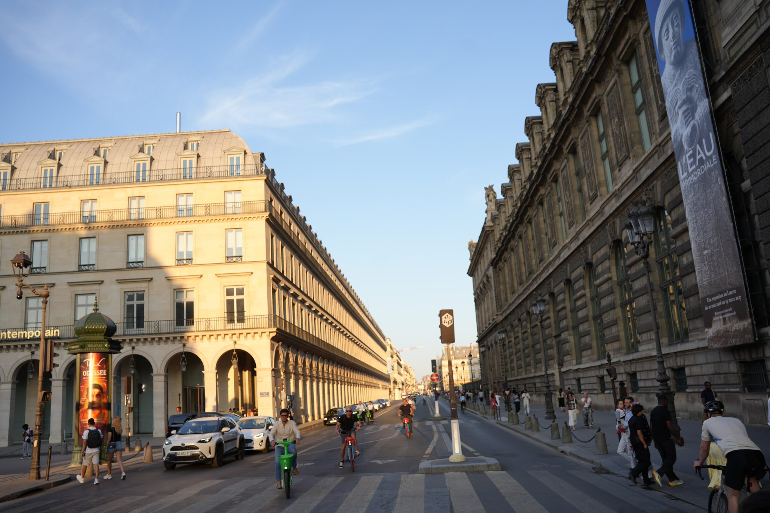Golden evening light on Rue de Rivoli beside the Louvre with pedestrians and cyclists in 2026