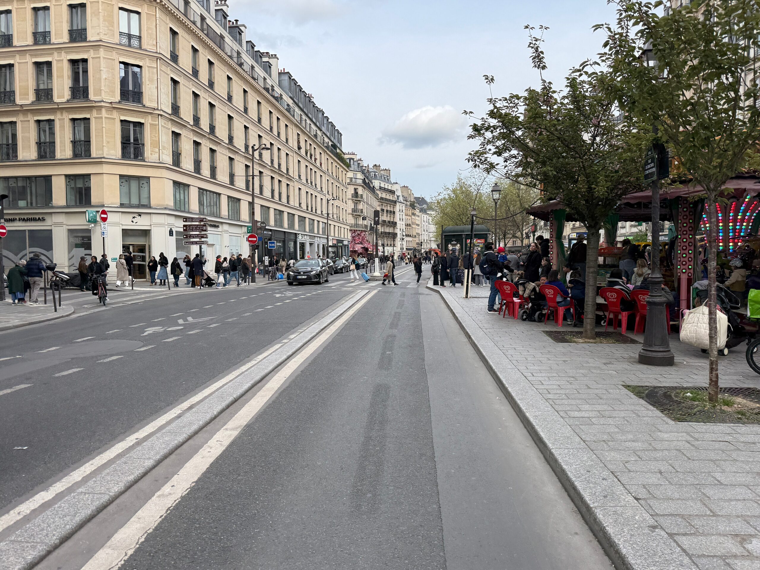 Current 2026 view of Rue de Rivoli in the Marais with pedestrians, cyclists and café terraces