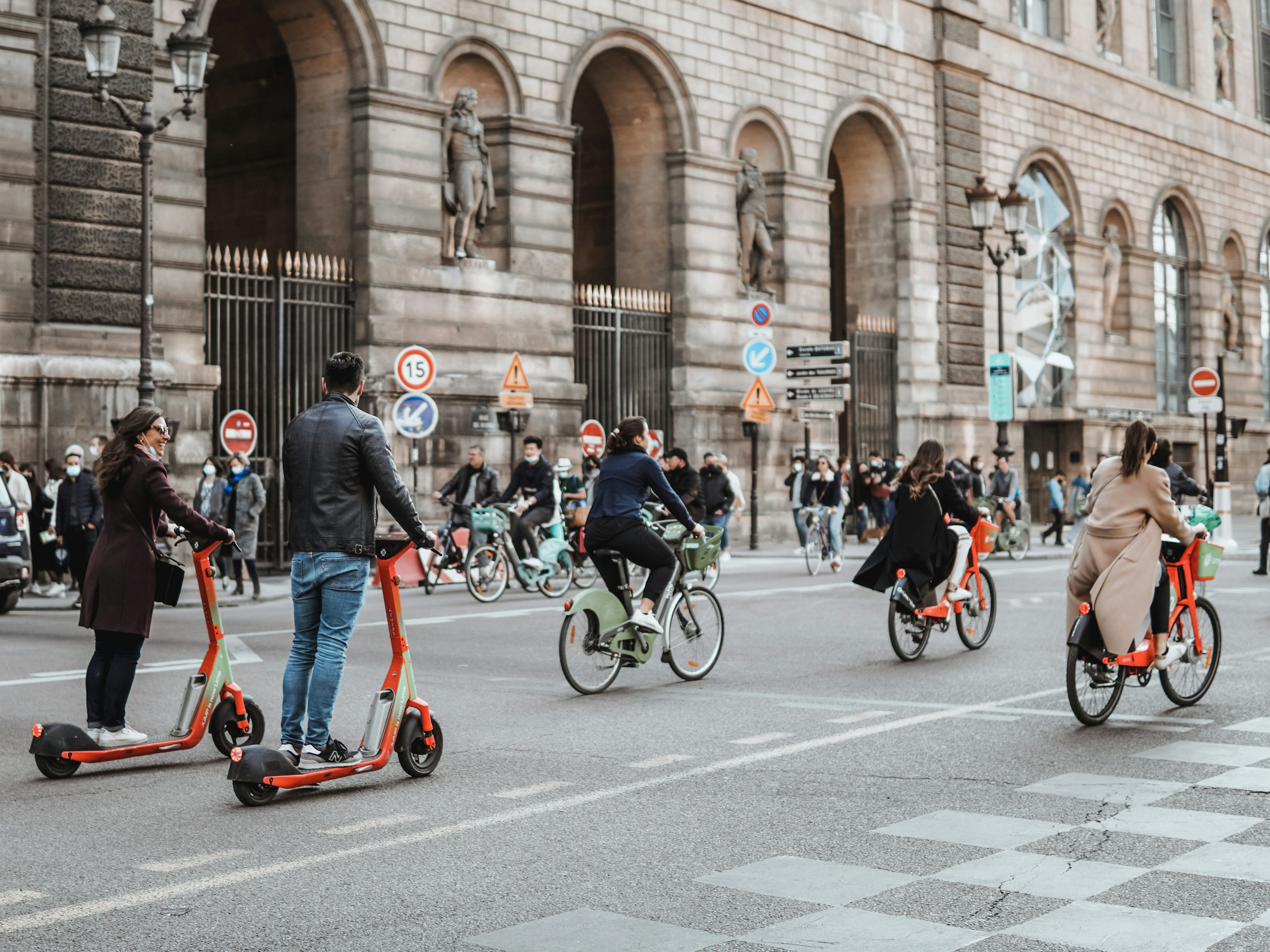Stylish pedestrians, women cyclists and scooter riders on Rue de Rivoli in front of the Louvre