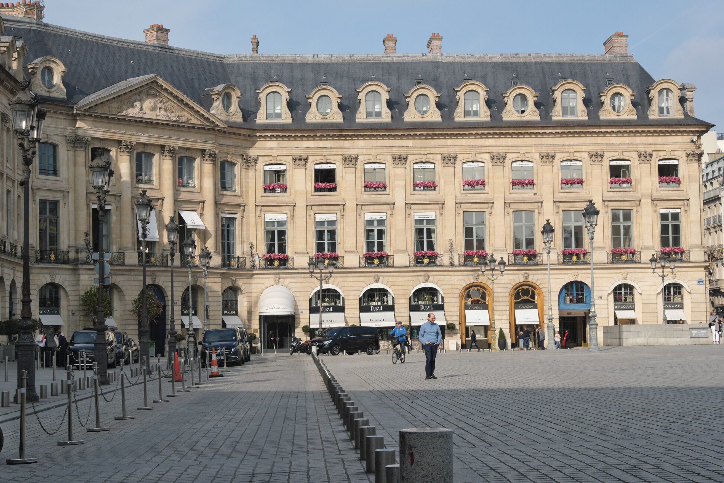 Pedestrians walking past sunlit Place Vendôme luxury façades near Rue Saint-Honoré
