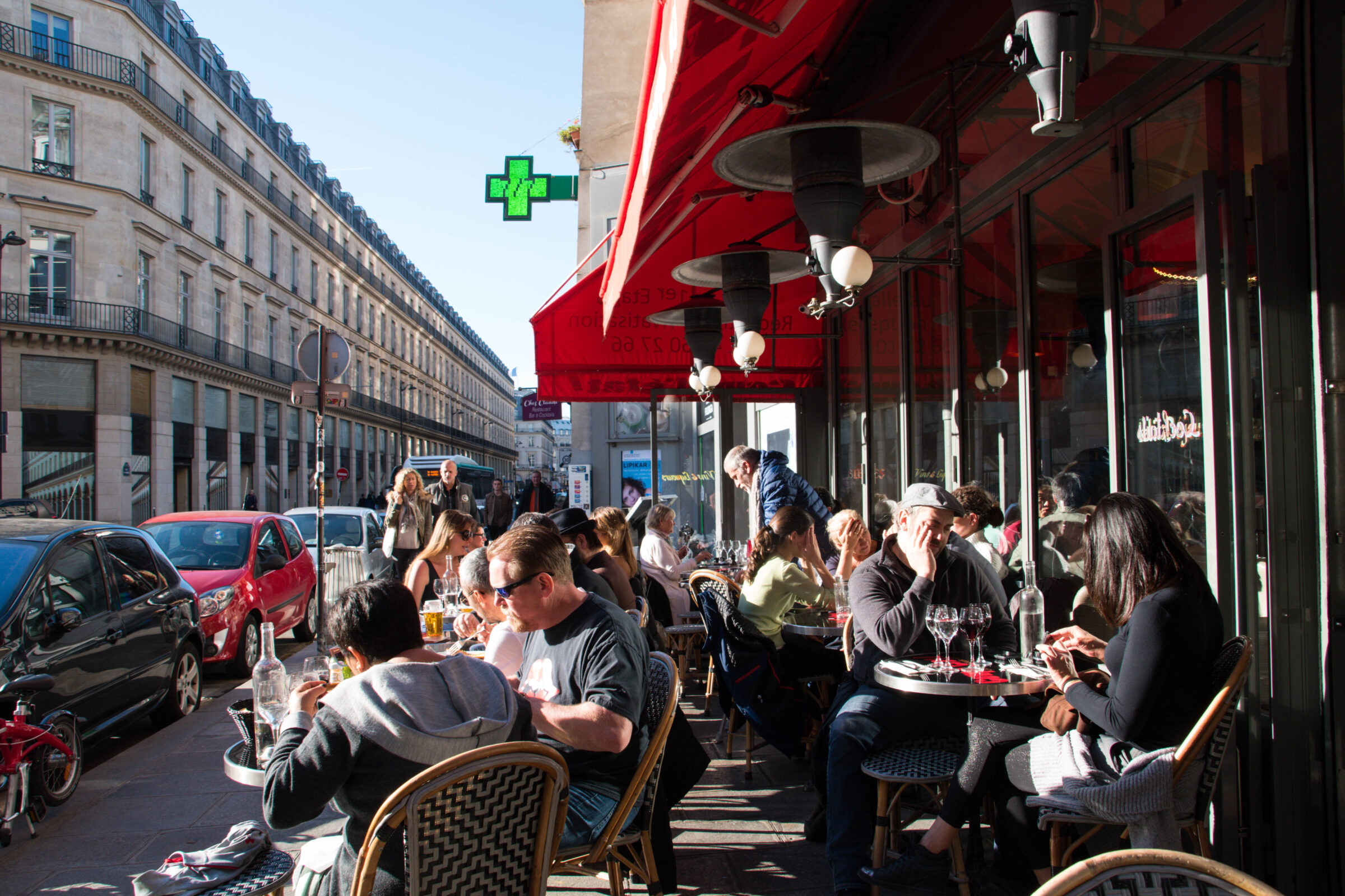 People seated at a lively sidewalk café at 164 Rue Saint-Honoré in Paris