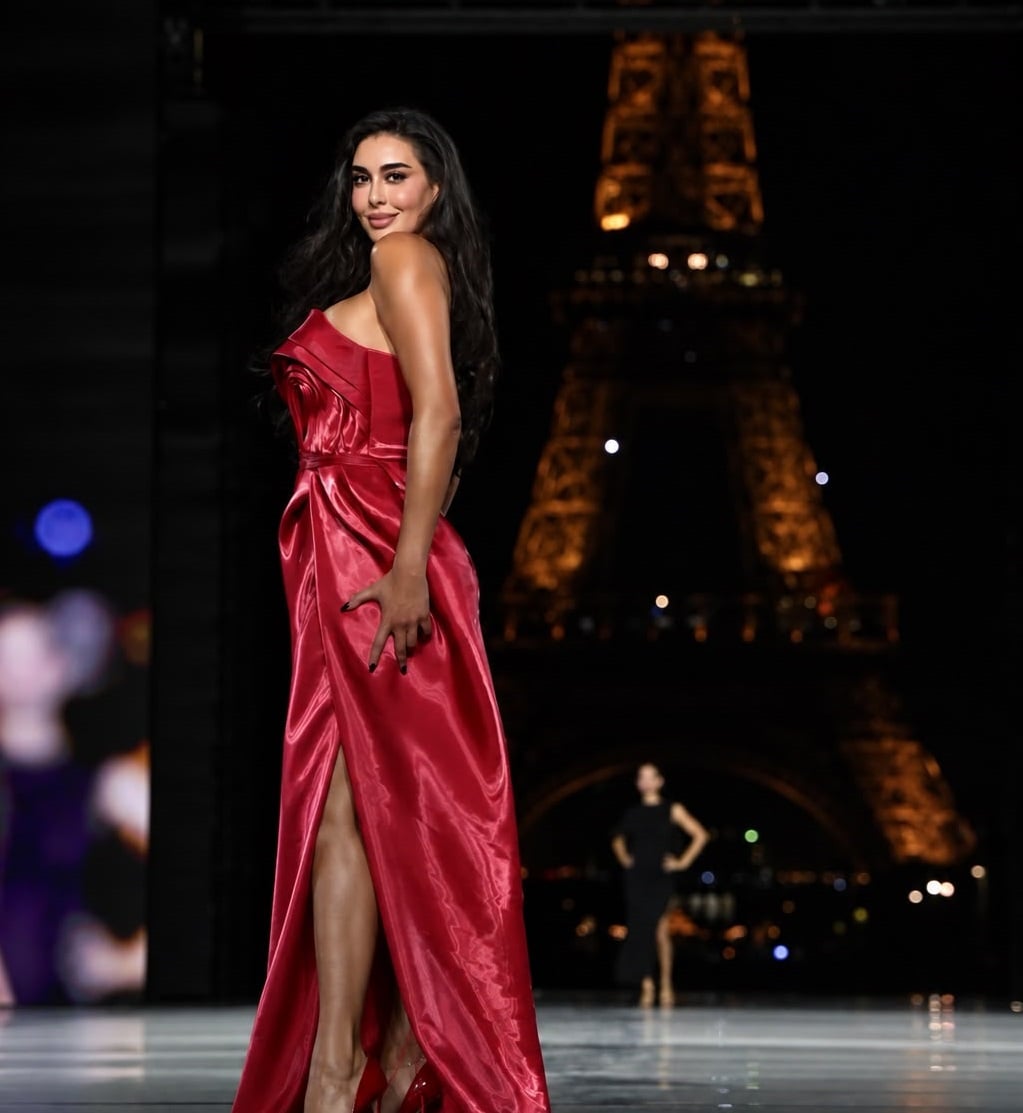 Yasmine Sabri in a red slit gown with the Eiffel Tower behind her