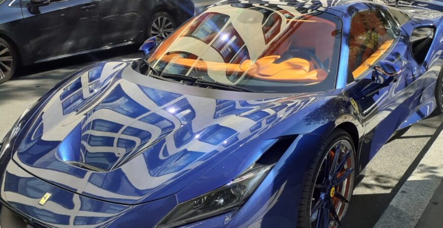 Street view outside Bvlgari Hotel Paris, with a blue sports car in the foreground