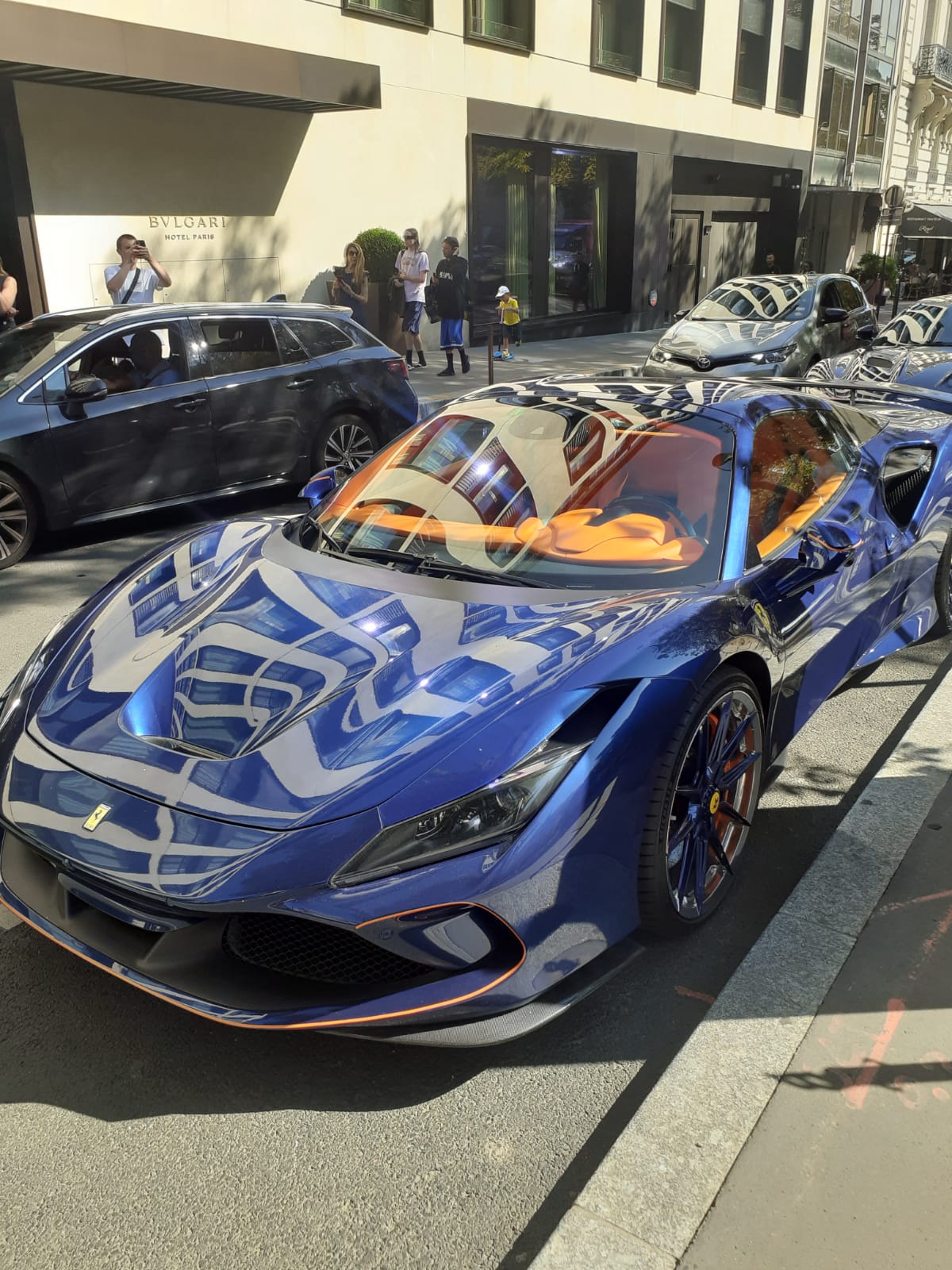 Street view outside Bvlgari Hotel Paris, with a blue sports car in the foreground
