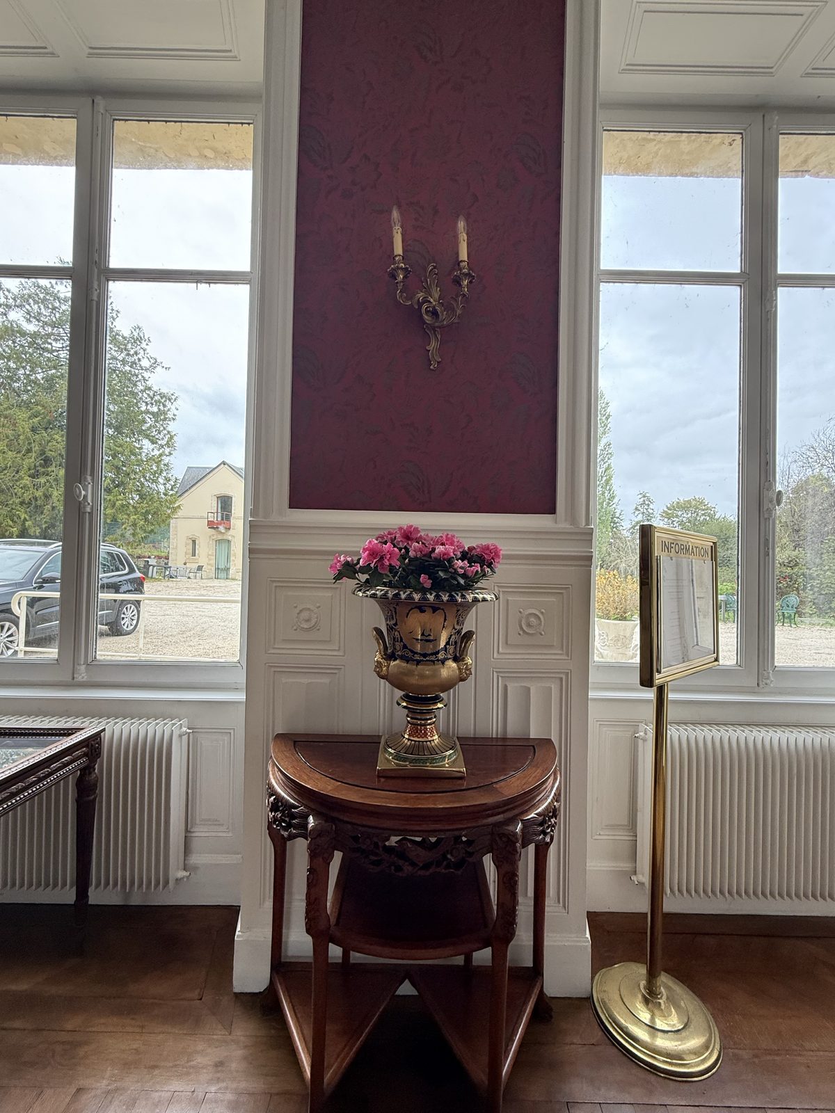 Period interior with red wall, windows and antique furniture at Château de Bellefontaine