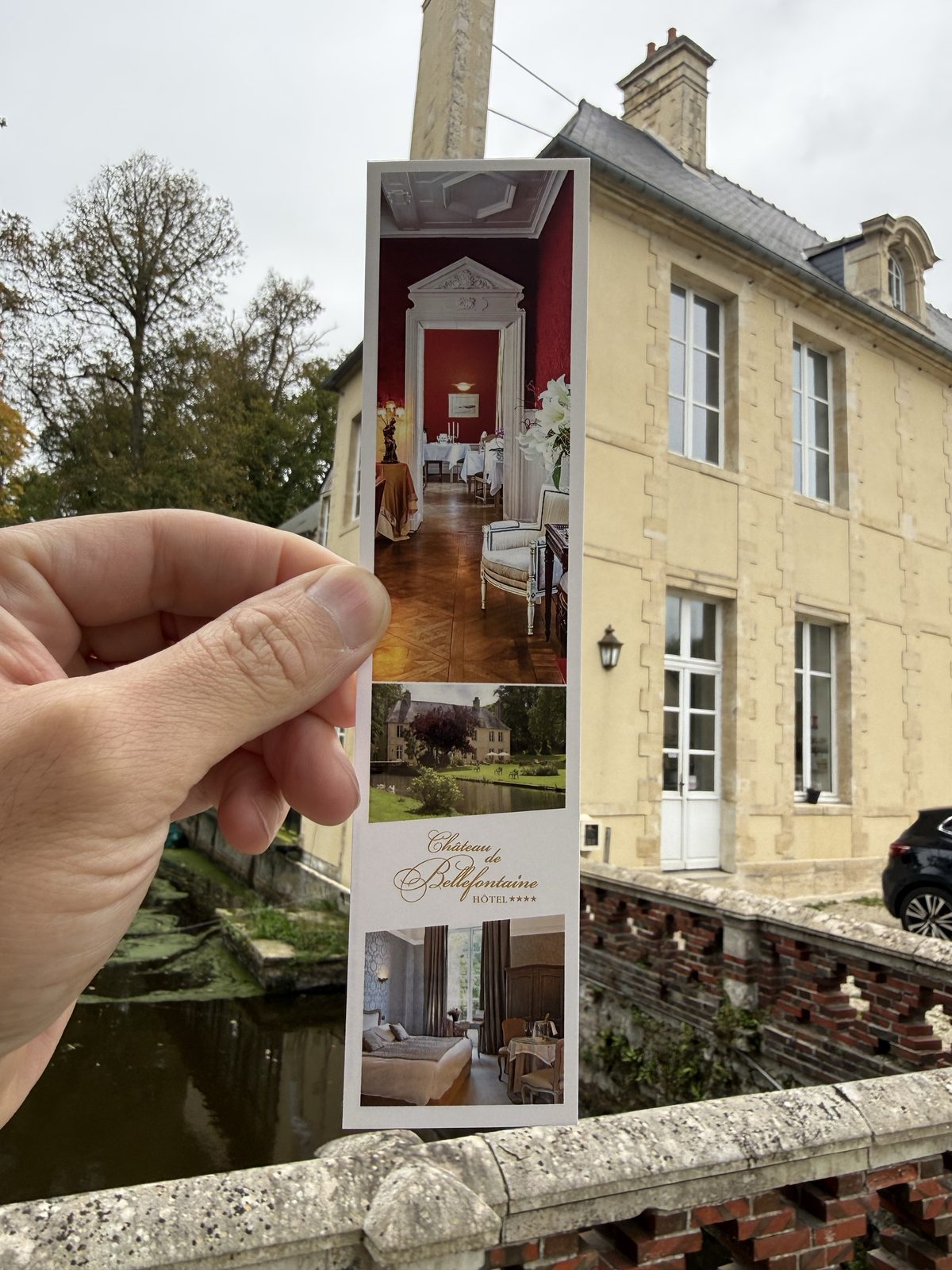 Original Château de Bellefontaine brochure held in front of the Bayeux château