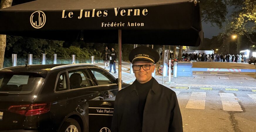 Christophe beneath the Le Jules Verne canopy with the illuminated Eiffel Tower behind him