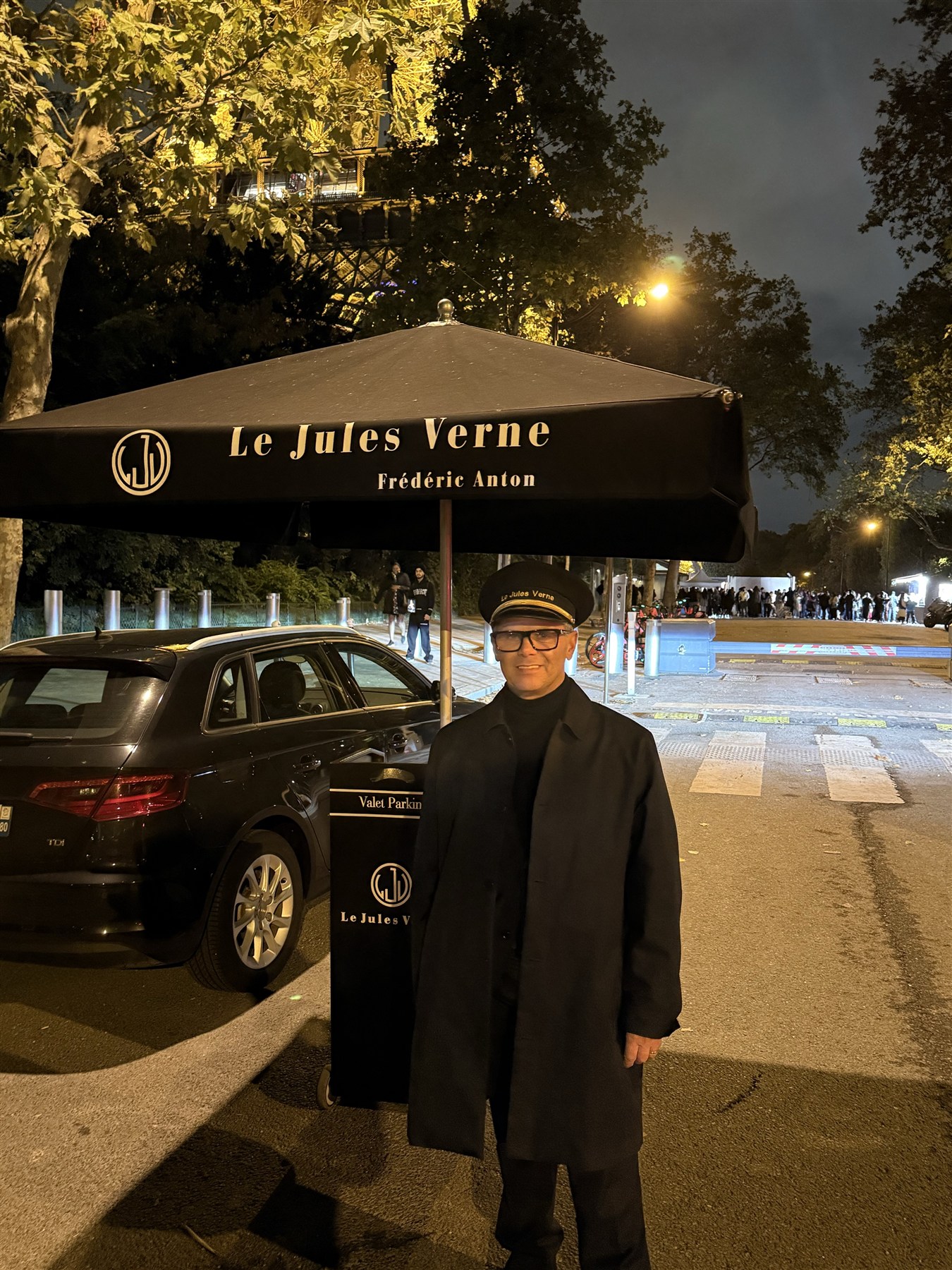 Christophe beneath the Le Jules Verne canopy with the illuminated Eiffel Tower behind him