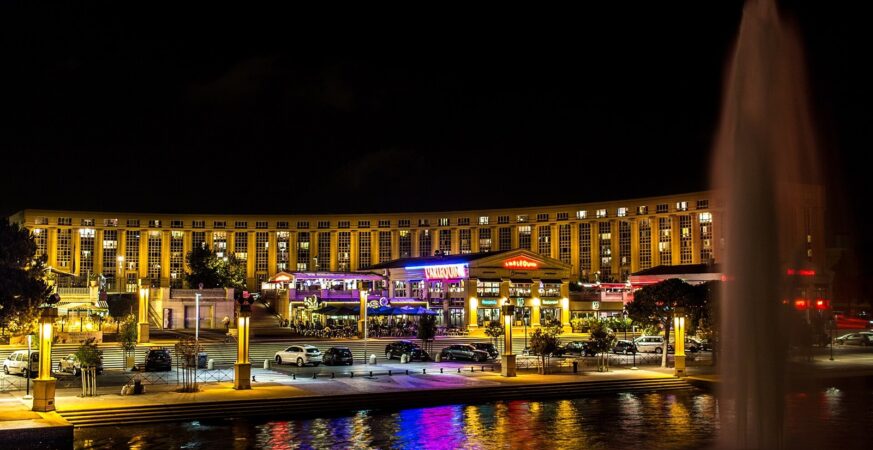 Illuminated buildings and fountain in Montpellier’s Antigone district at night
