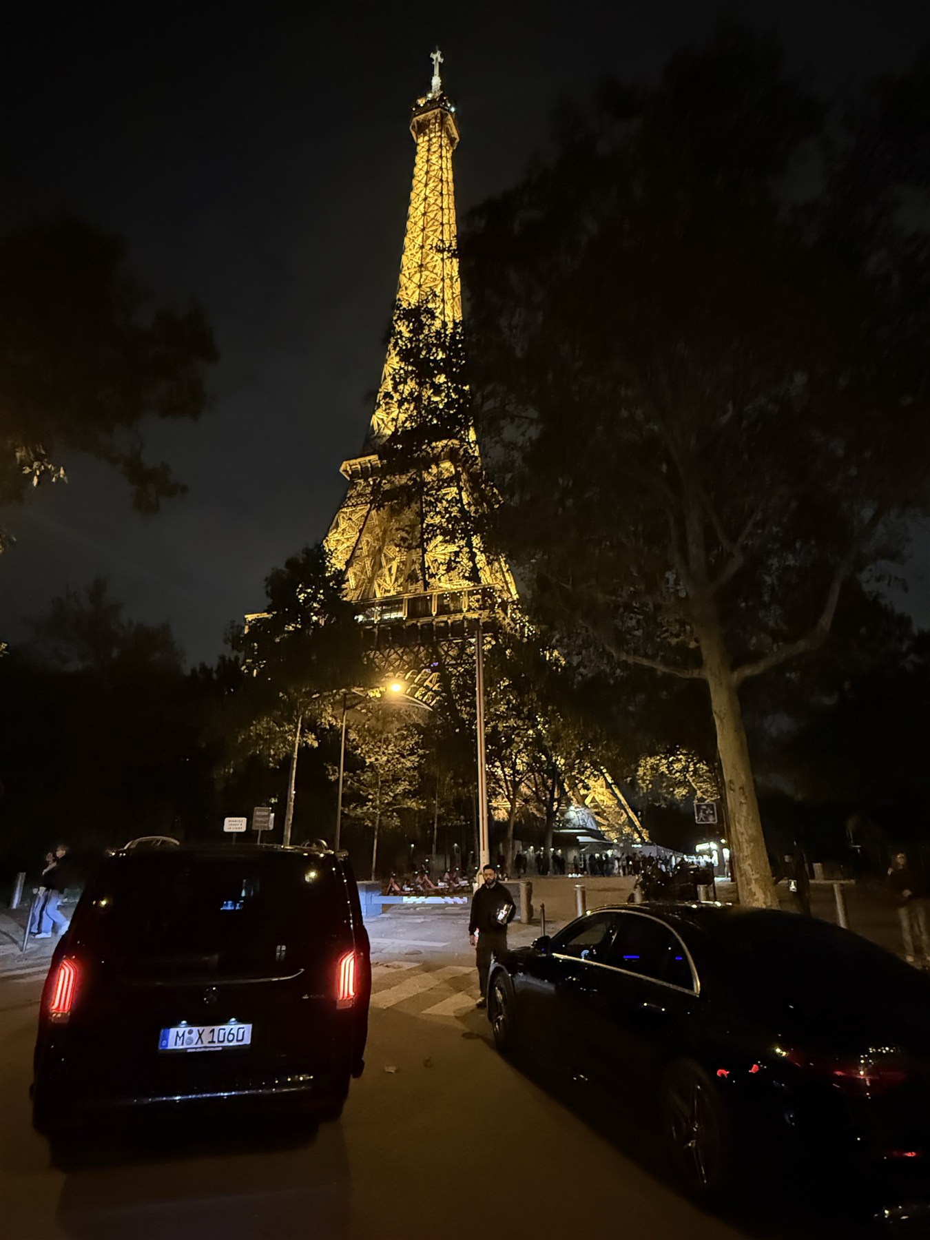 The illuminated Eiffel Tower above cars near the restaurant