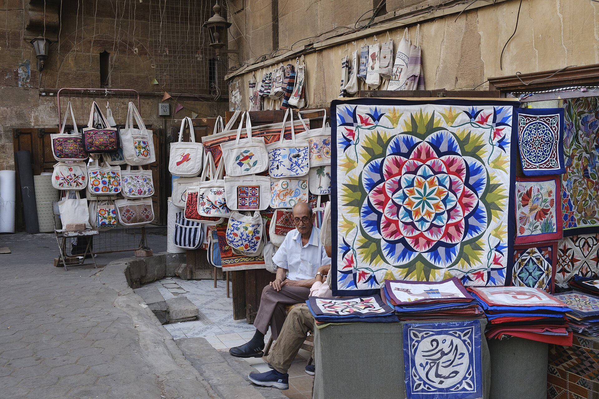 A maker and shop display khayamiya panels and bags in the historic market, where tent architecture meets contemporary design.