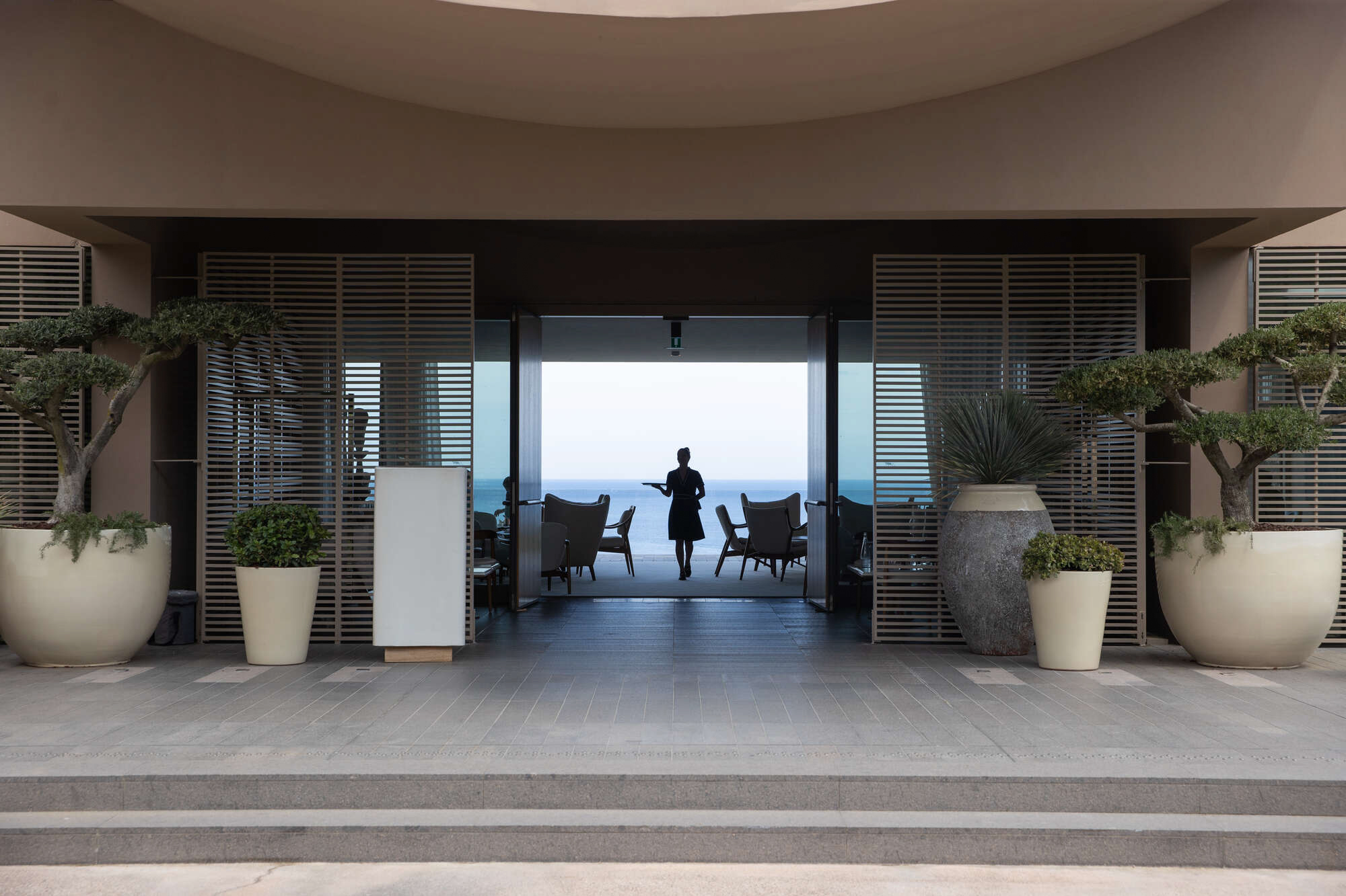 Sea-facing entrance of La Réserve Ramatuelle with a staff member framed in the doorway