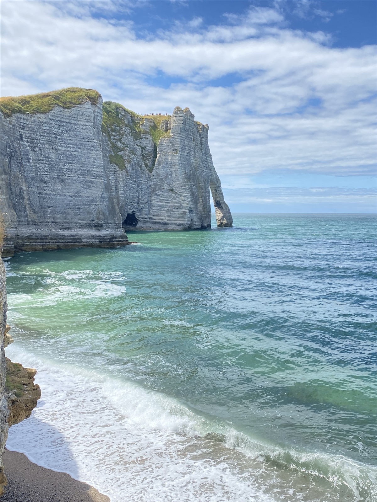 A view from beach level reveals layers of chalk and a natural arch above the Channel.