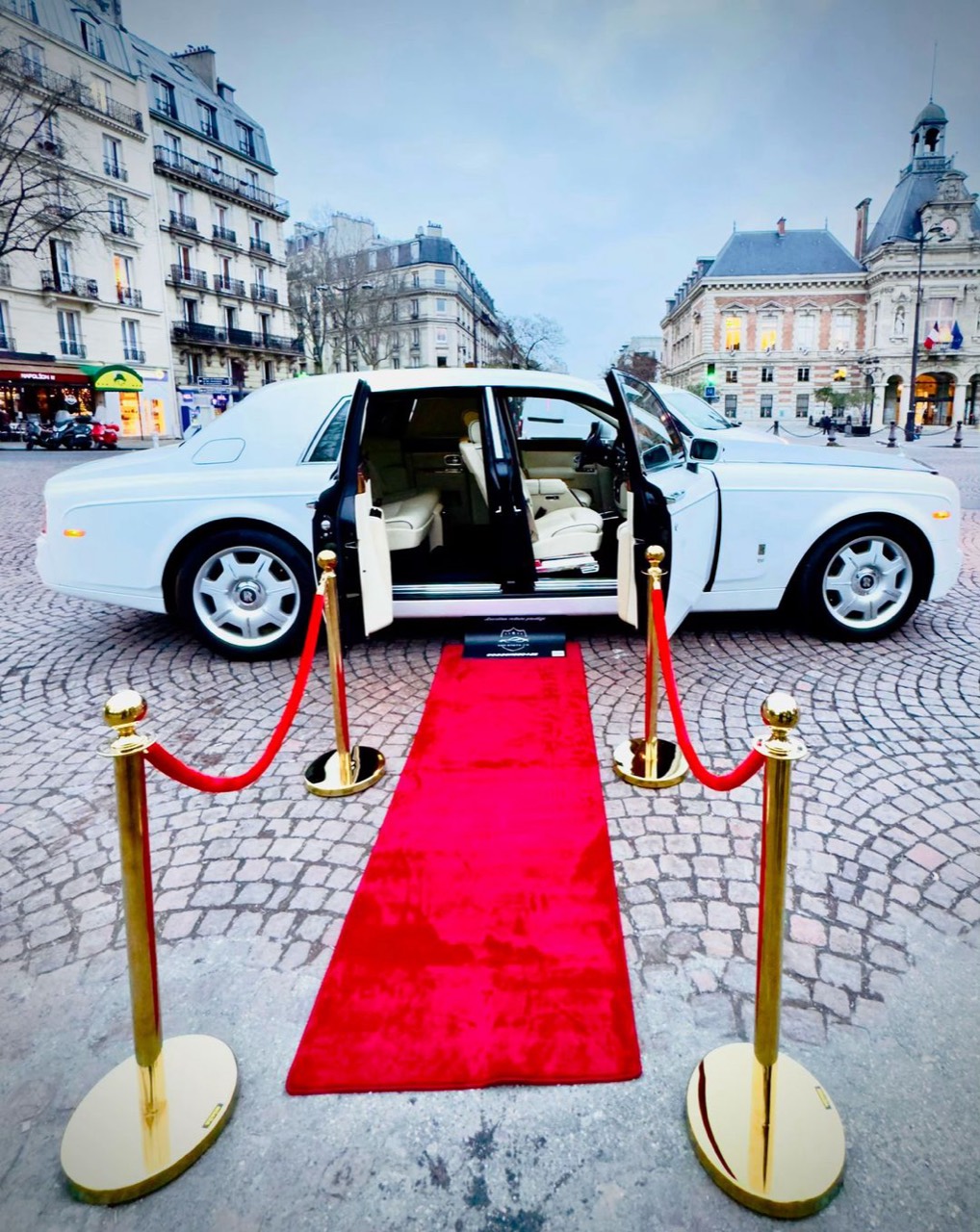A white Rolls-Royce with its door open beside a red carpet in Paris