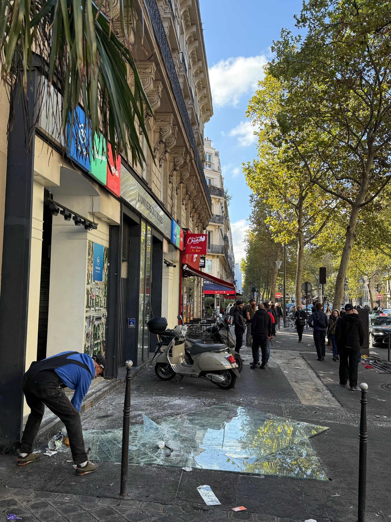 A worker begins clearing shattered glass from a Paris pavement on Sunday morning