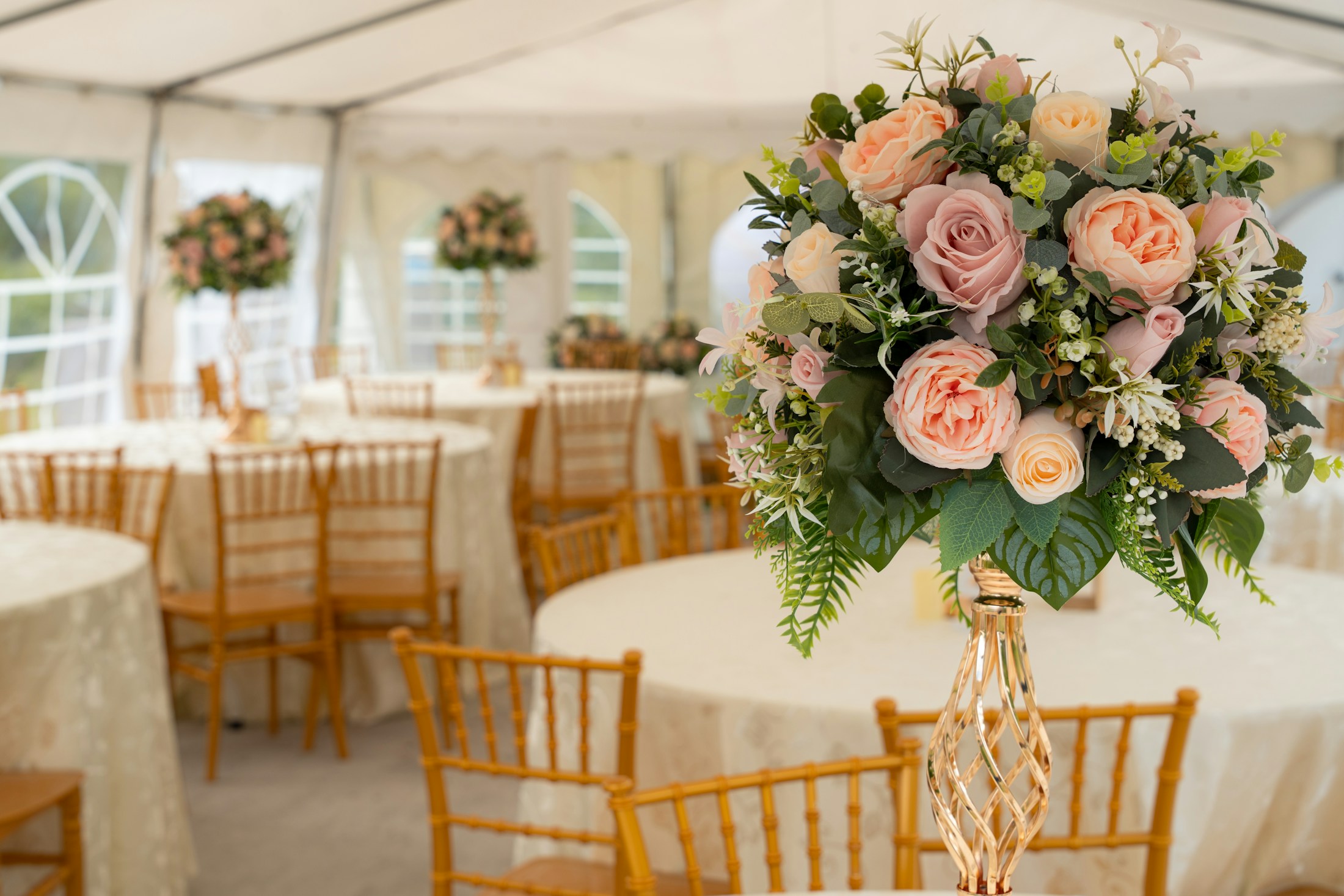 Floral wedding table beneath a bright white event tent