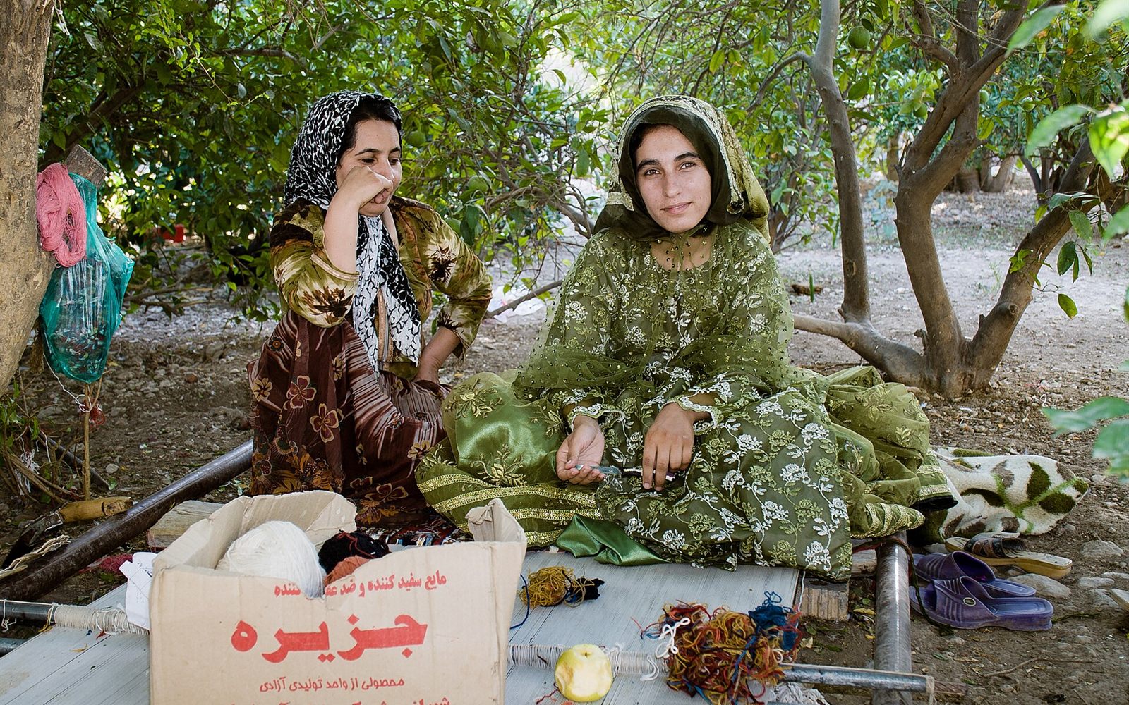 Deux sœurs qashqaïes près d’un métier horizontal à Firuzabad, dans le Fars : les visages précèdent le motif achevé.