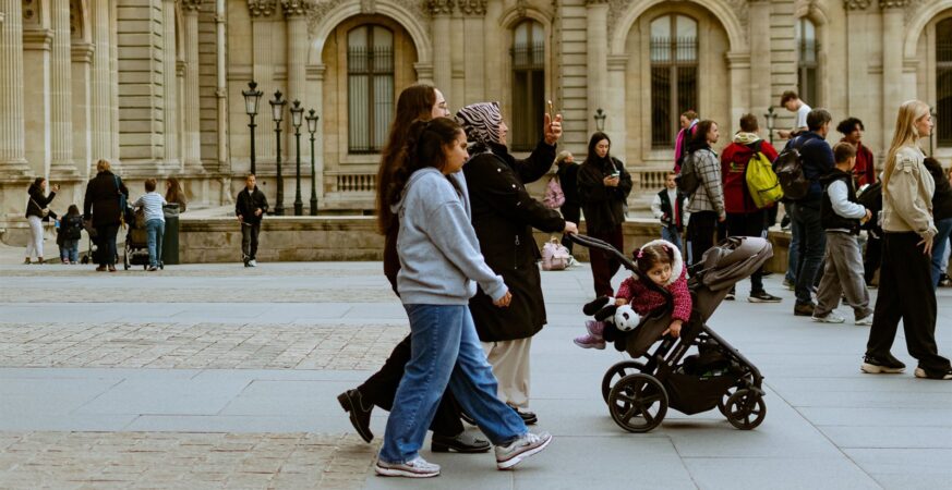 بالغون وأطفال مع عربة صغيرة أمام متحف اللوفر في باريس