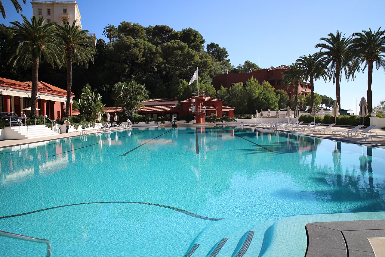 Vue large de la piscine et des bâtiments rouges du Monte-Carlo Beach