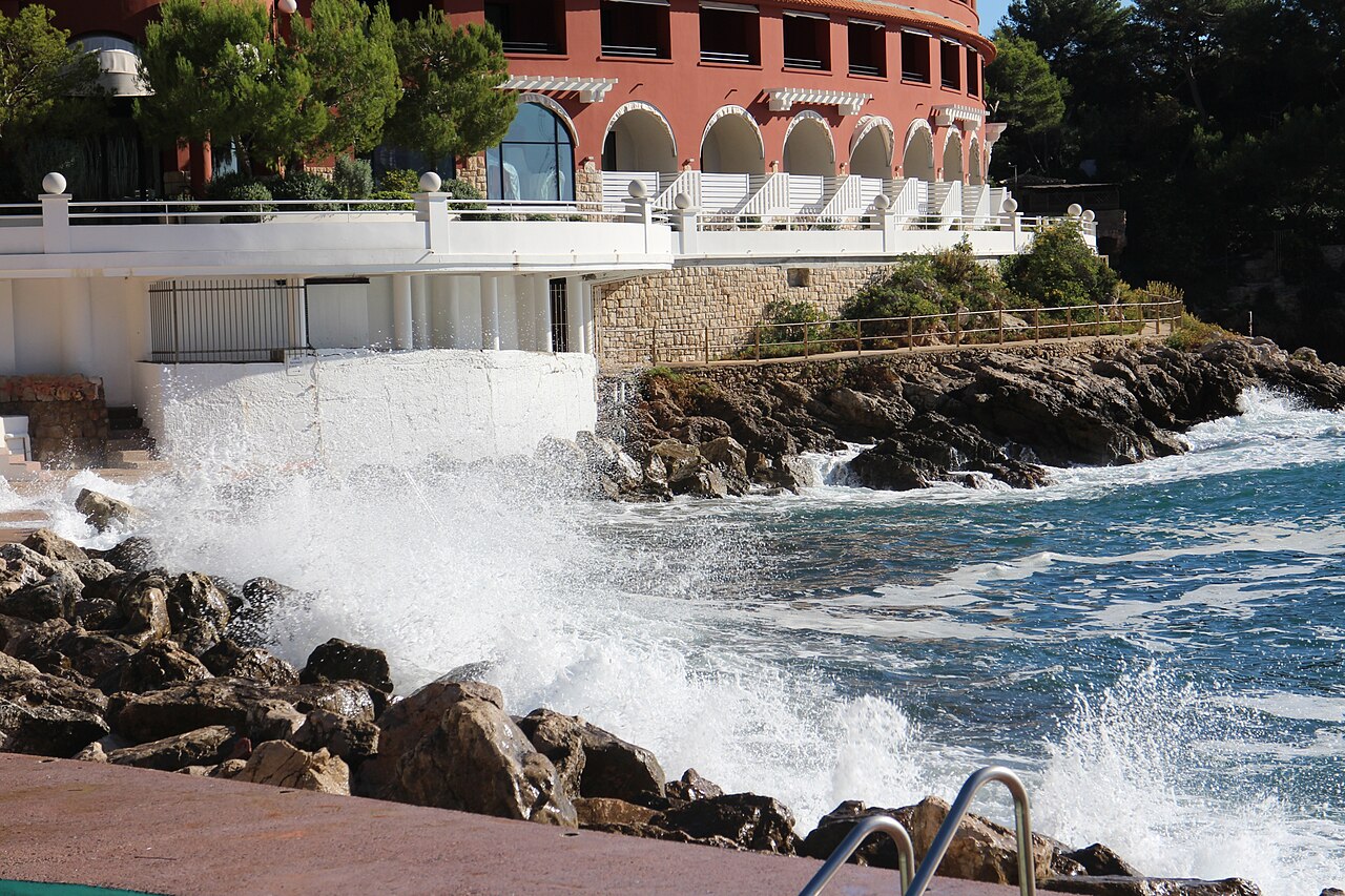 Façade rouge incurvée du Monte-Carlo Beach au-dessus du rivage rocheux