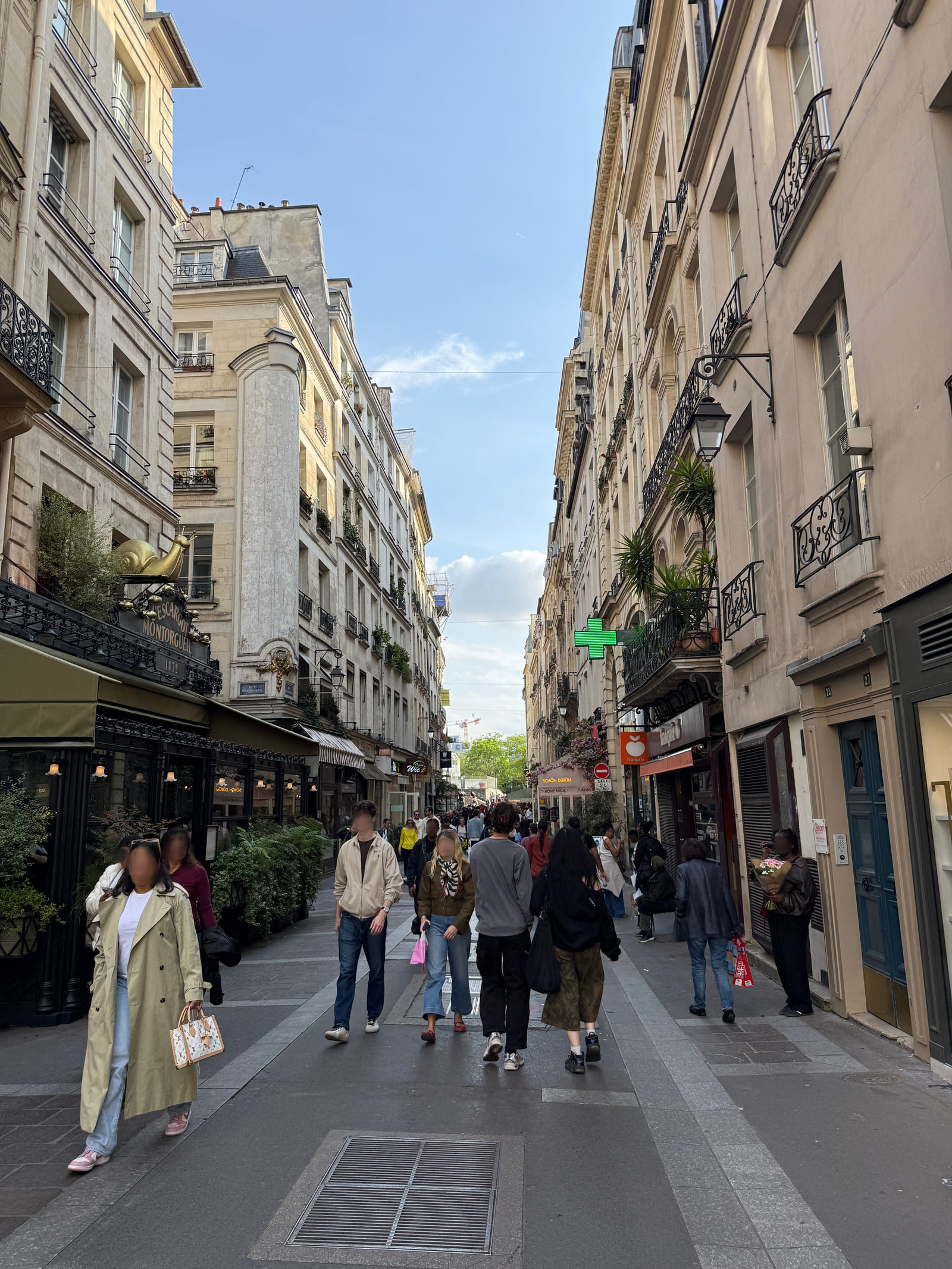 Vertical view along Rue Montorgueil with pedestrians, shopfronts and the L’Escargot sign.