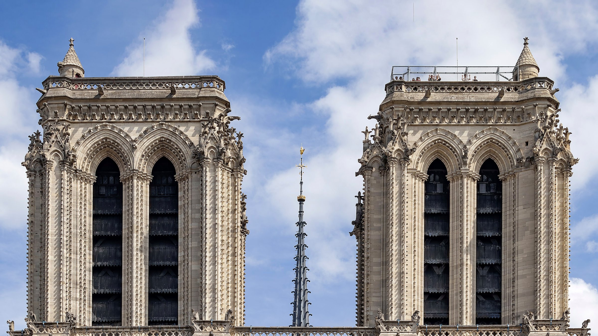 Les deux tours de Notre-Dame de Paris encadrant la flèche reconstruite de Viollet-le-Duc sous un ciel bleu en juillet 2026