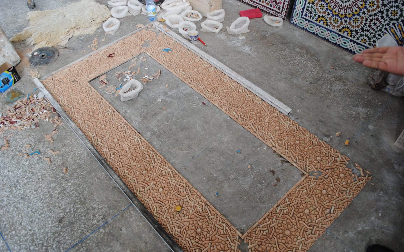 A zellige panel assembled face-down before it is fixed and lifted; geometry comes before the reveal of colour.